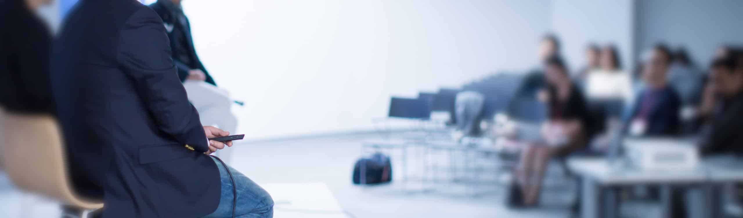 Focus on presentation remote held by panel presenter during conference