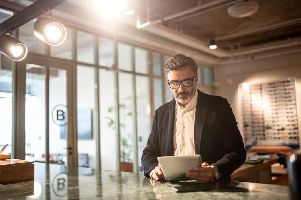 Mature businessman using digital tablet at modern office